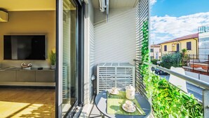 En balkon med et bord dækket til the, et fjernsyn på væggen og udsigt til gaden nedenunder.