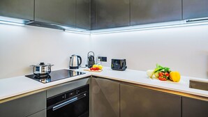 Et moderne køkken med rustfrie hårde hvidelementer, indbygget ovn og en hvid bordplade.