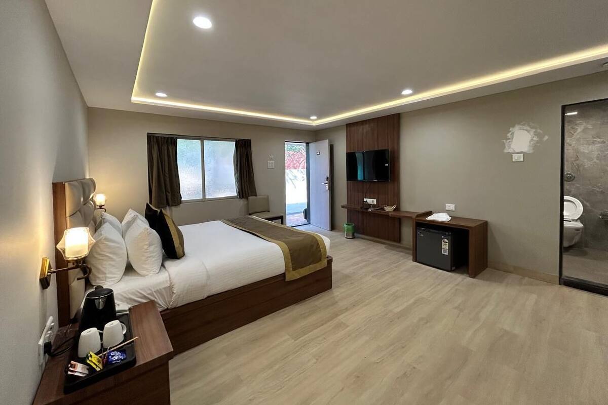 Een moderne hotelkamer met een groot bed, nachtkastjes, een televisie en een zichtbare badkamer door een open deur.
