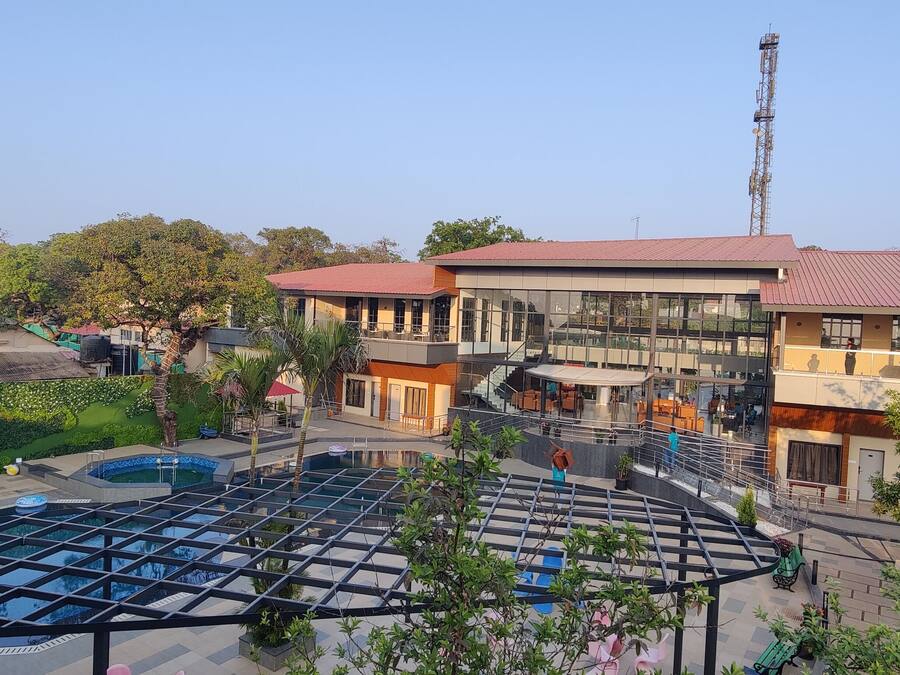 A hotel with a swimming pool, outdoor seating, and a red-roofed building.