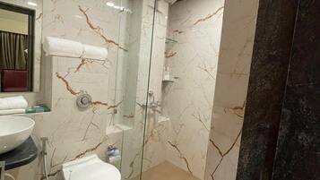 A modern bathroom with a glass-enclosed shower, a white toilet, and a marble-tiled sink.