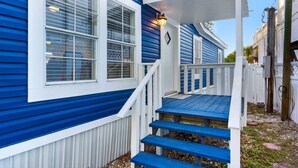 A blue house with white trim, a front porch with steps, and a light fixture on the porch.