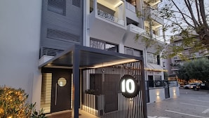 A modern building with a prominent number '10' sign, a gated entrance, and a parking area with a handicapped parking symbol. - 10 Apartments & Suites Athens (Kallithea)