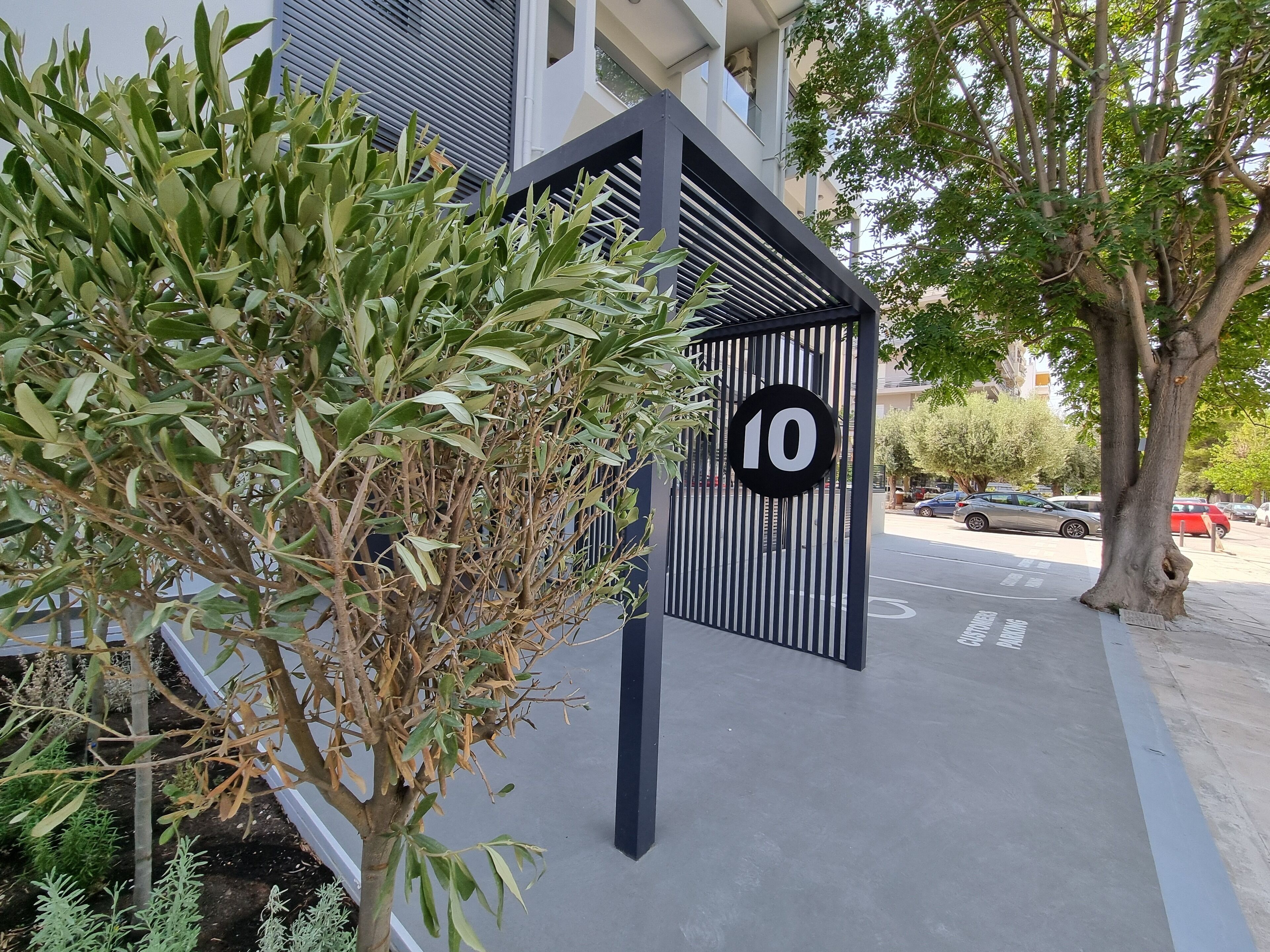 A gated entrance with a number 10 sign, a tree, and a building in the background.
