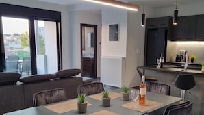 A modern dining area with a rectangular table, black upholstered chairs, and small potted plants. - 10 Apartments & Suites Athens (Kallithea)