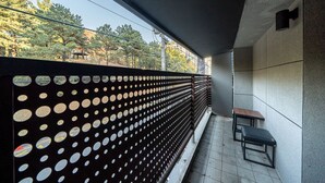 Un espacio moderno al aire libre con un banco y una valla metálica decorativa, con vistas a árboles y edificios al fondo.