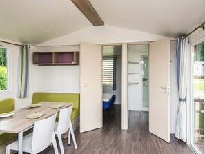 Une chambre compacte et moderne, dotée d’un coin repas, d’un petit lit et d’une douche.