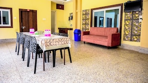 Un coin repas avec une table dressée pour six personnes, un canapé et un téléviseur fixé au mur.
