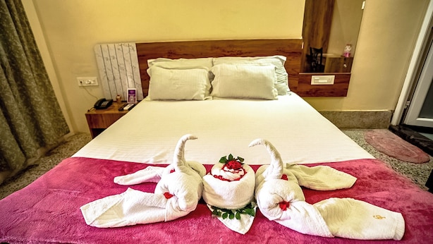 Une chambre d’hôtel avec un grand lit, deux oreillers, une table de chevet avec un téléphone et un miroir.