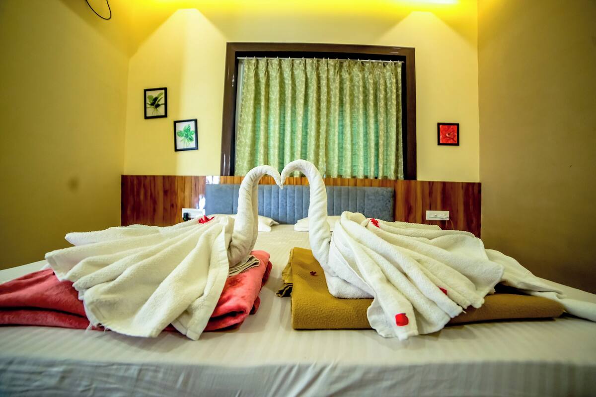 A hotel room with two beds, each with a towel arranged in a heart shape.