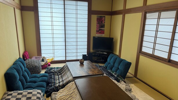 Un tradizionale salotto giapponese con pavimento in tatami, un tavolino in legno e sedute imbottite blu.