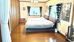 Una camera da letto con un letto grande, un'armadio in legno, una finestra con tende, una sveglia a muro e un quadro incorniciato.