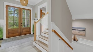 Eine Treppe mit hölzernen Geländern und Blick ins Freie durch ein großes Fenster.