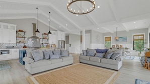 Ein geräumiges Wohnzimmer mit zwei Sofas, einem großen Teppich und einer Küche im Hintergrund.