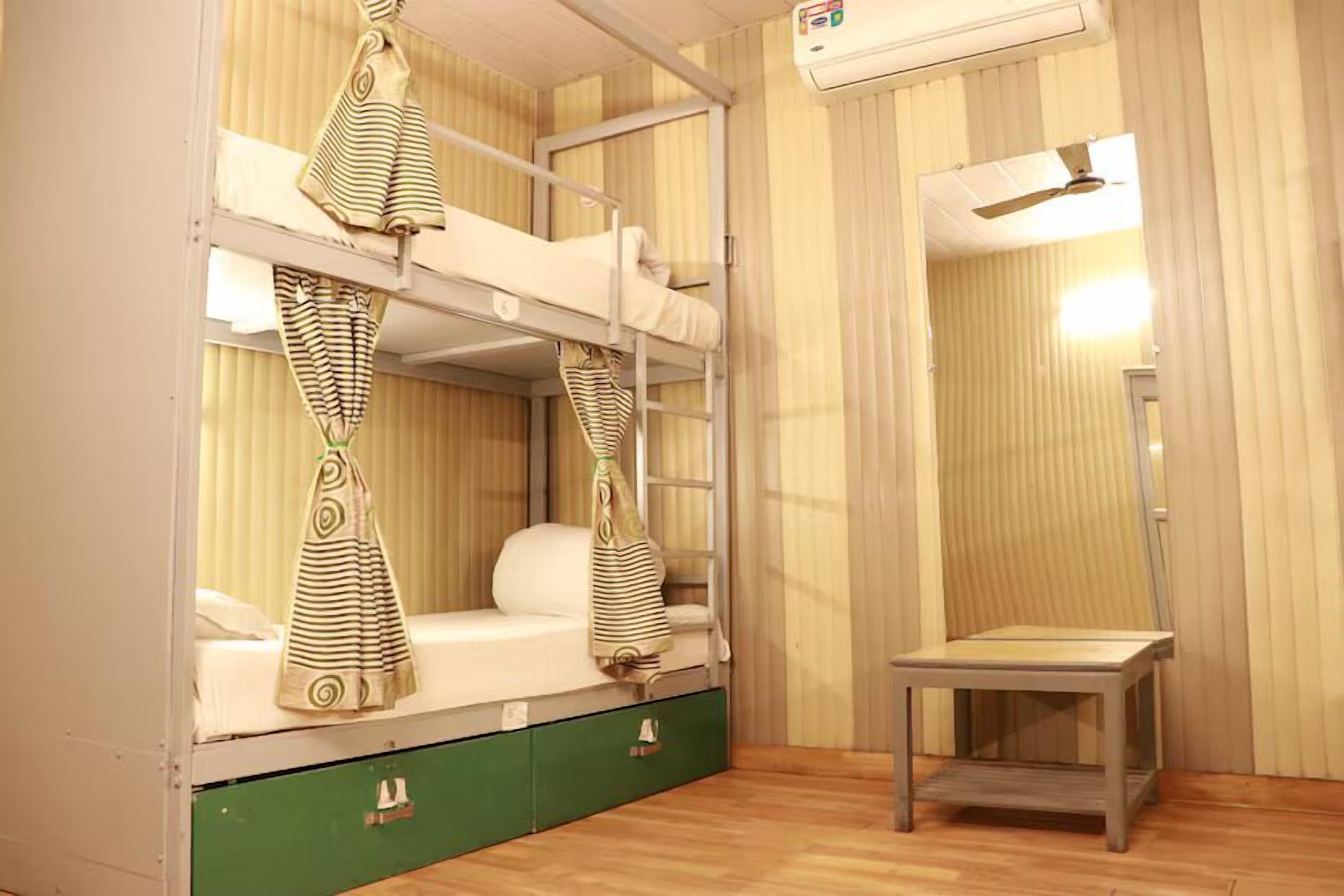 A bunk bed room with a small table and a ceiling fan.