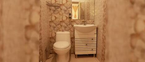 A bathroom with a stone-patterned wall, a toilet, and a sink with a mirror above it.