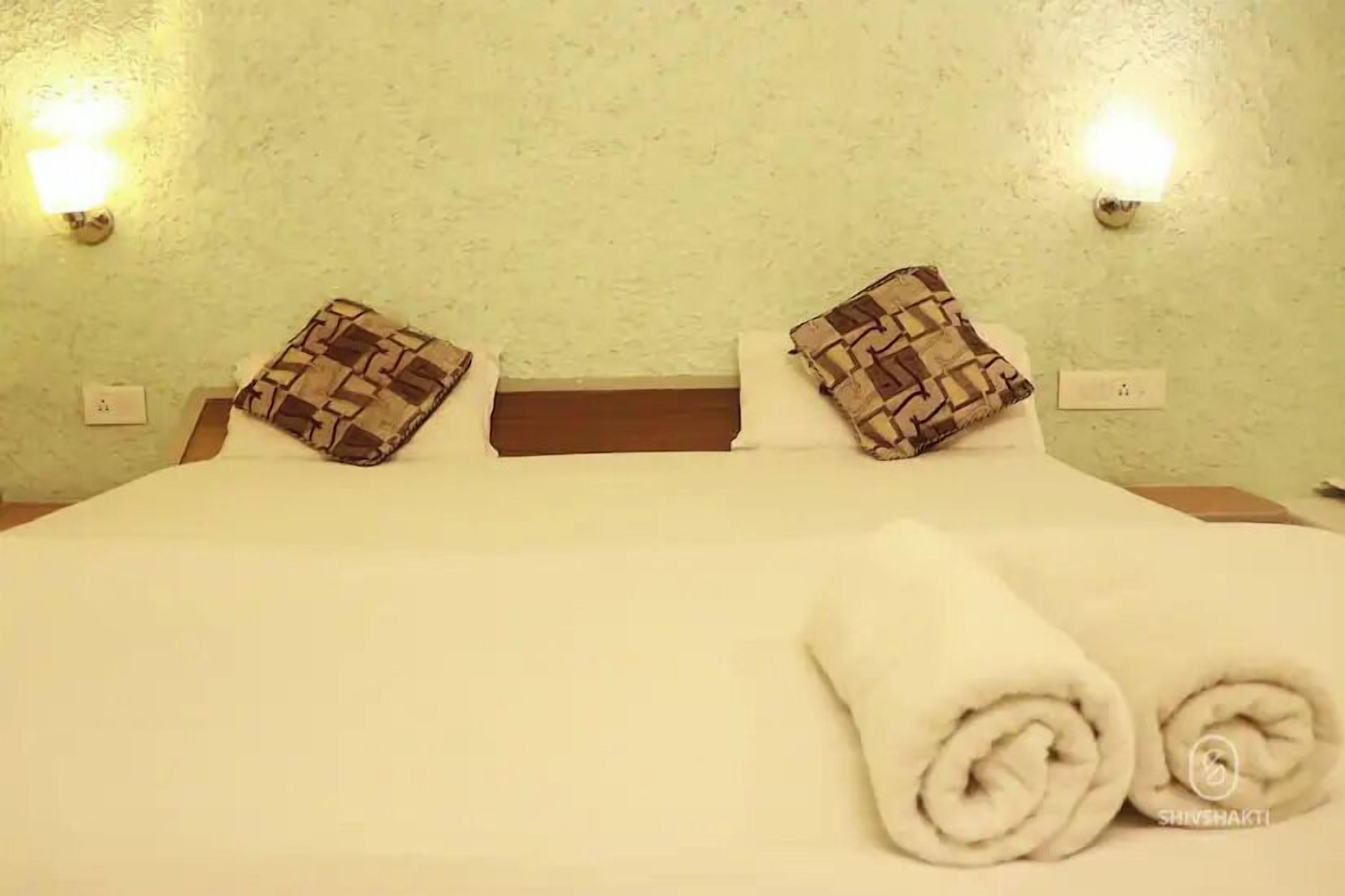Ein ordentlich gemachtes Bett mit zwei Kissen, einer weißen Bettdecke und zwei gerollten Handtüchern.