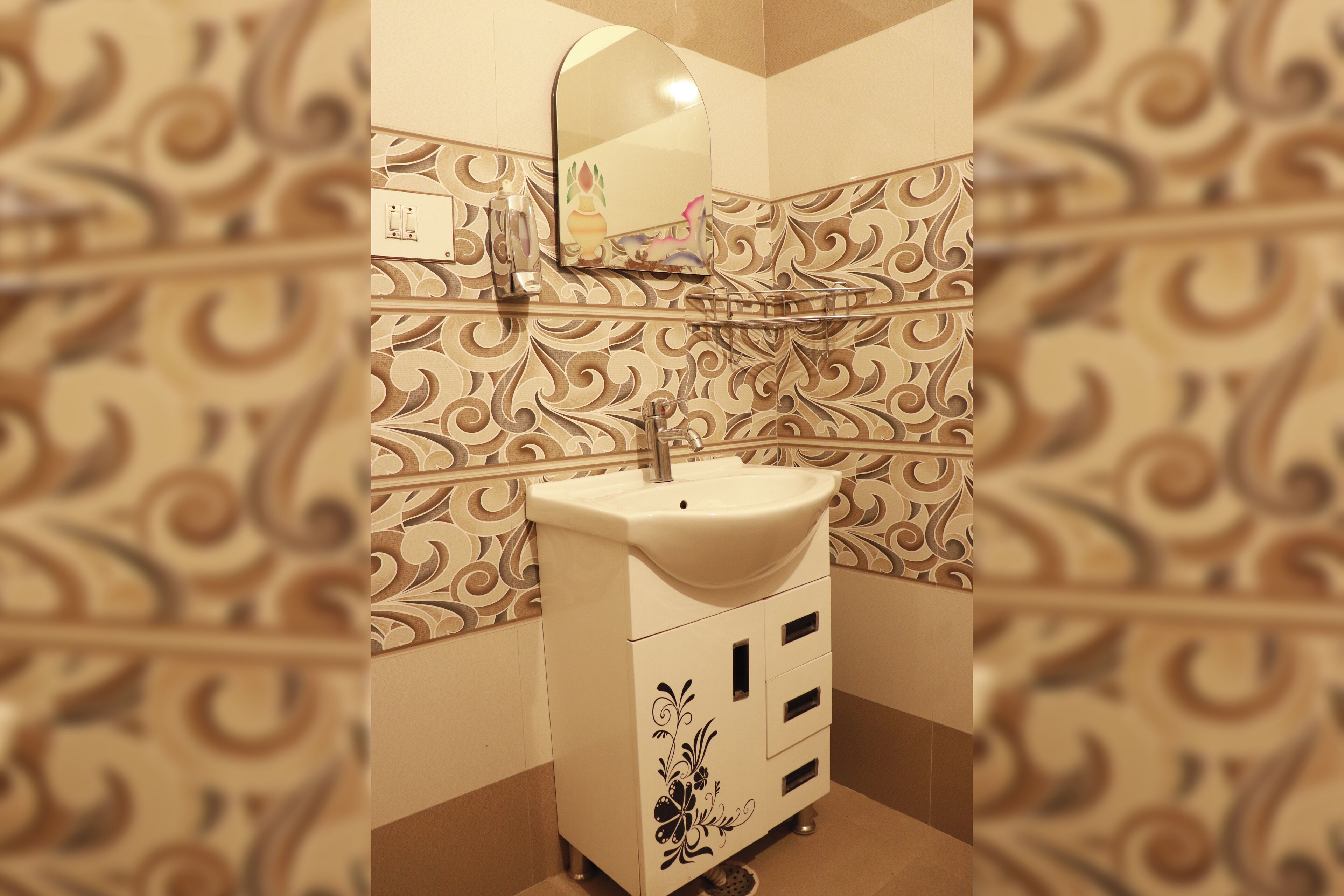 Une salle de bain avec un lavabo blanc, un miroir et des carreaux décoratifs sur les murs.