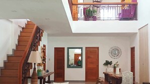 A spacious living area with a curved blue sofa, a coffee table, and a staircase leading to an upper level.