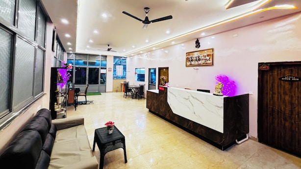 A modern hotel lobby with a reception desk, seating area, and a ceiling fan.