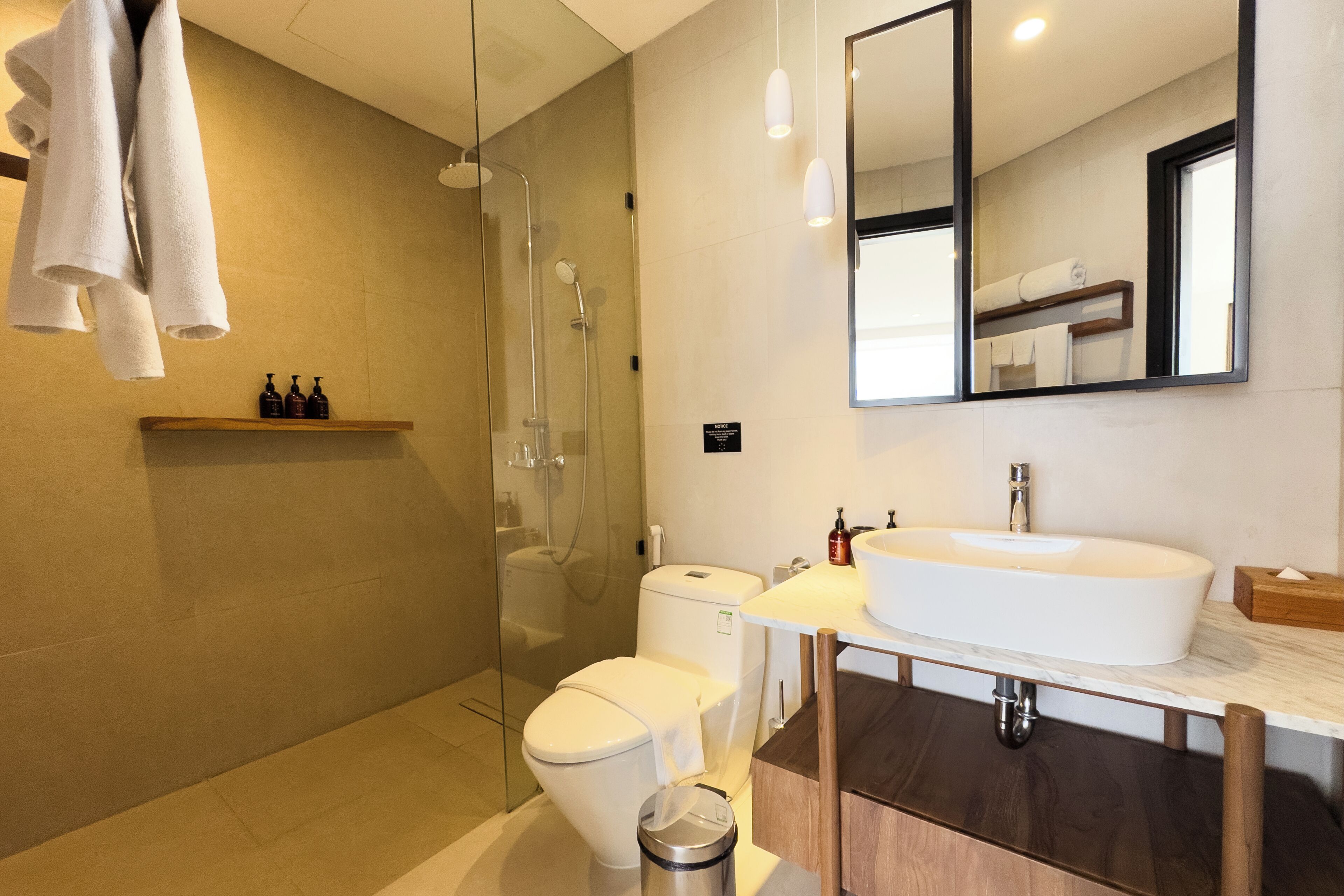 Een moderne badkamer met een douchecabine van glas, een wit toilet, een groot wastafel en een spiegel boven de wastafel.