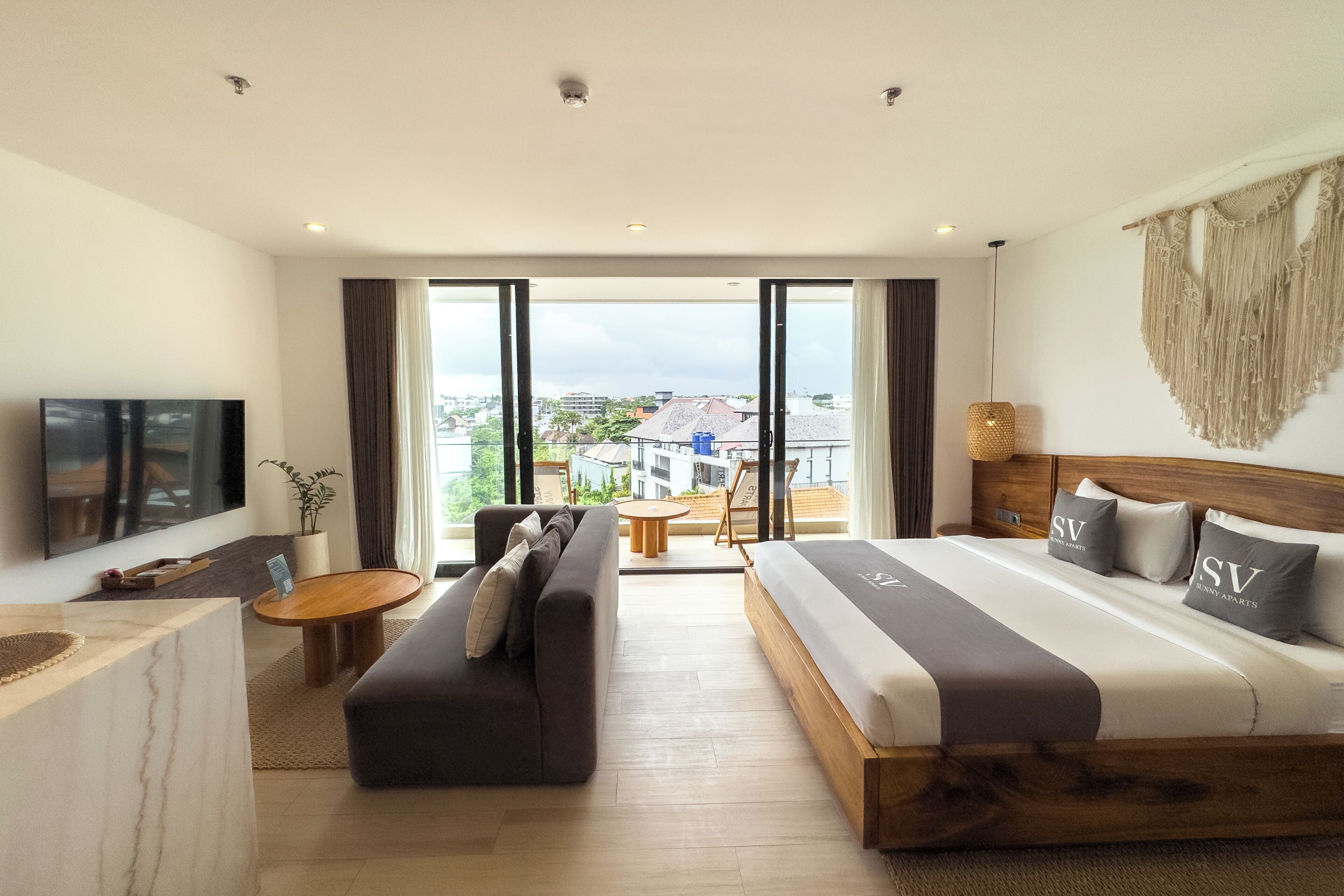 Una habitación de hotel con cama, sofá, televisor y balcón con vistas.