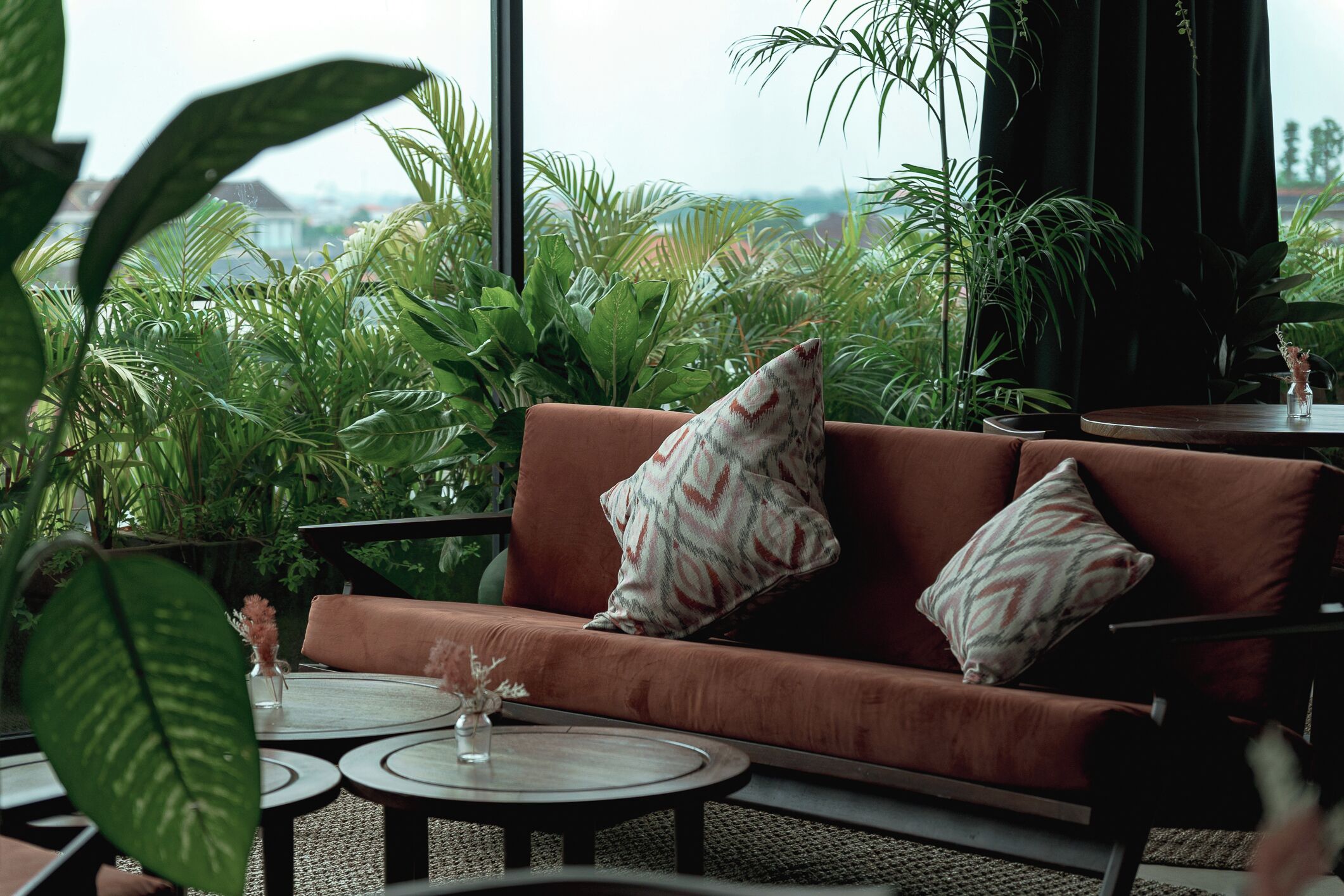 A cozy seating area with a brown sofa, two patterned pillows, and a small table with a vase.