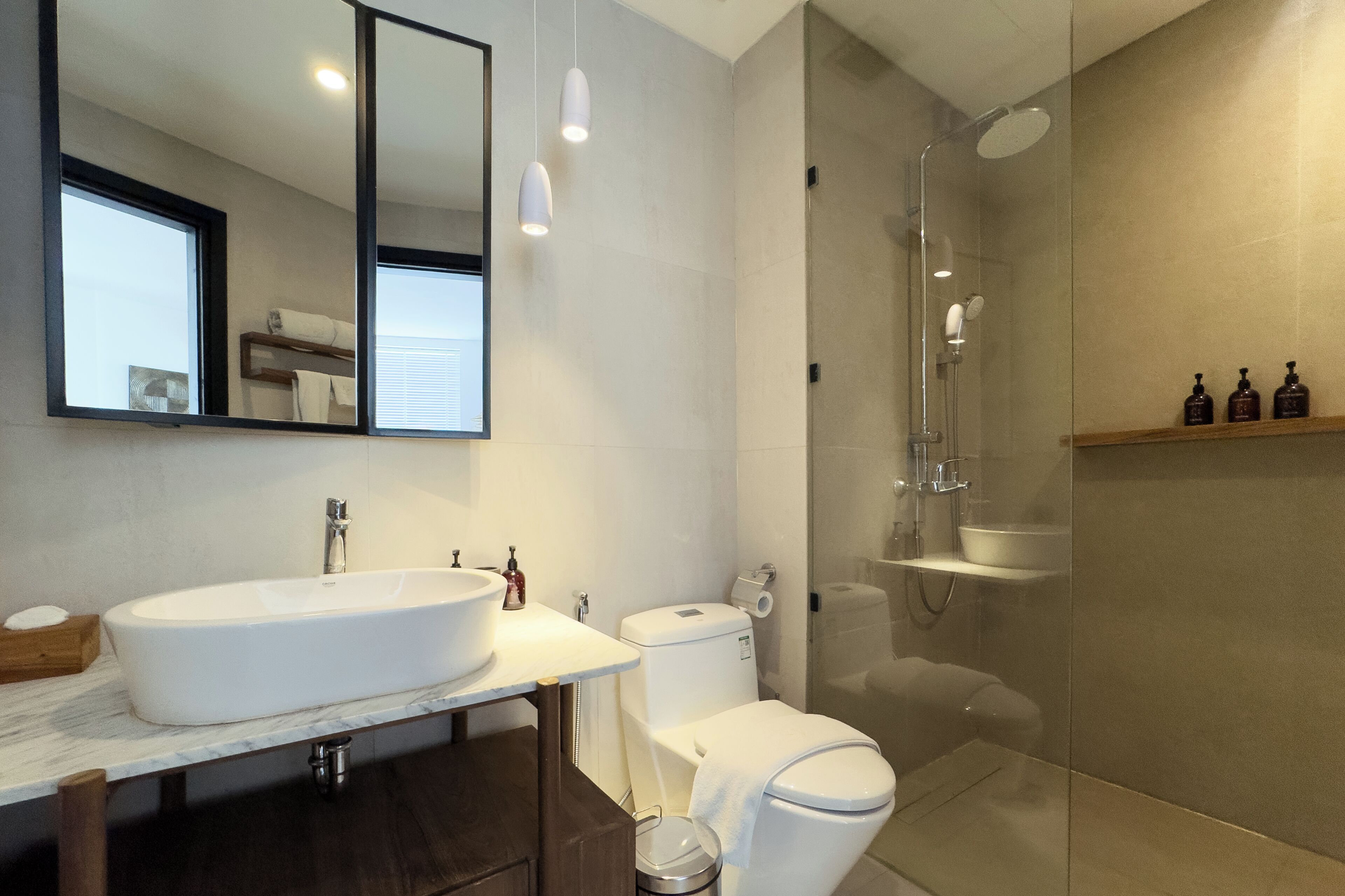 A modern bathroom with a large sink, toilet, and glass-enclosed shower.