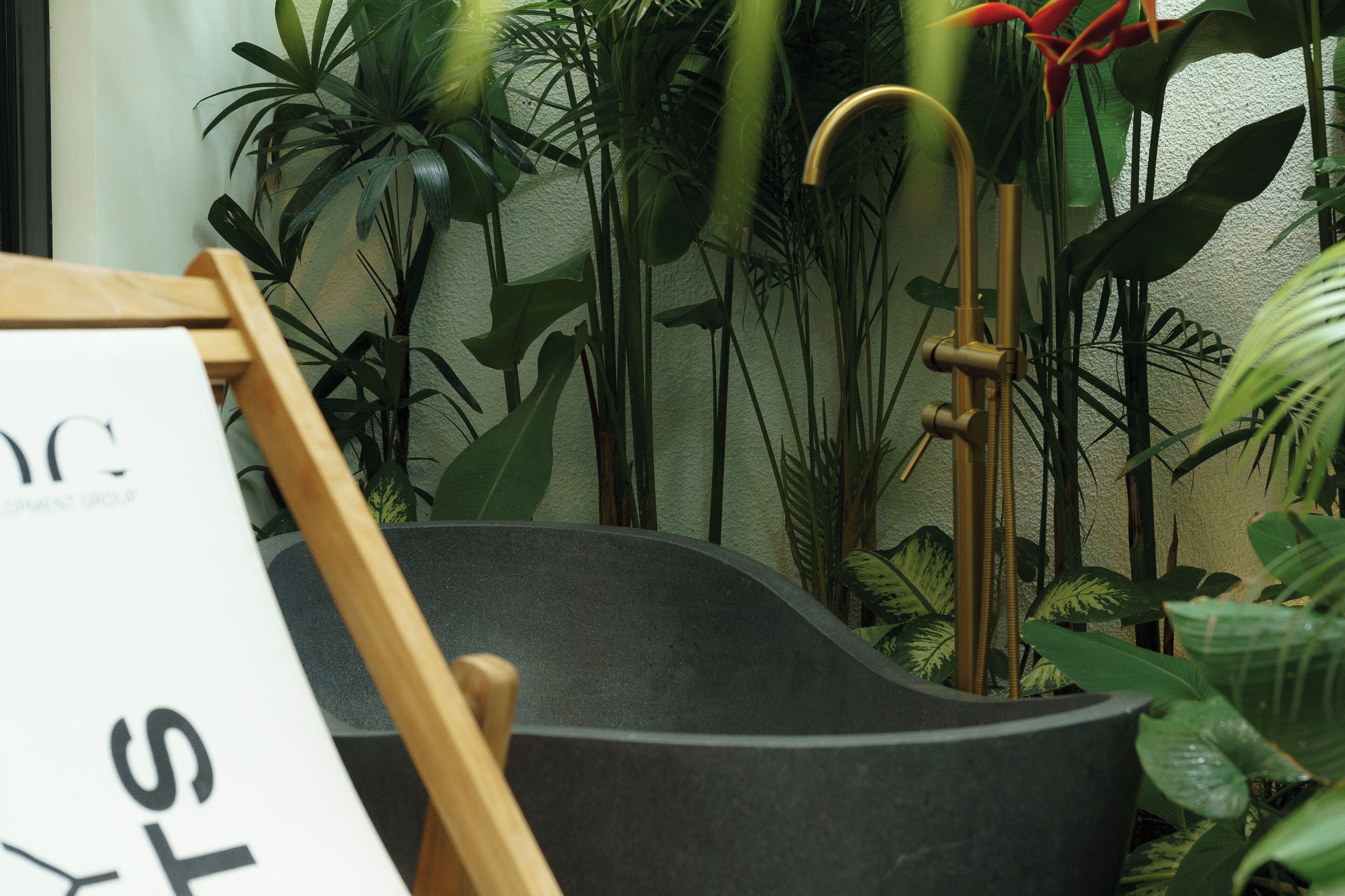 A room with a black bathtub, wooden furniture, and various green plants.