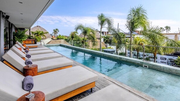 Zona junto a la piscina con sillones de descanso y vistas a una piscina.