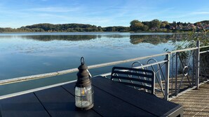 Une vue sur le lac, avec une table et des chaises, une lanterne et une balustrade donnant sur l’eau.