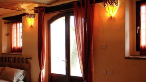 A room with a bed, a window with curtains, and wall-mounted lighting.