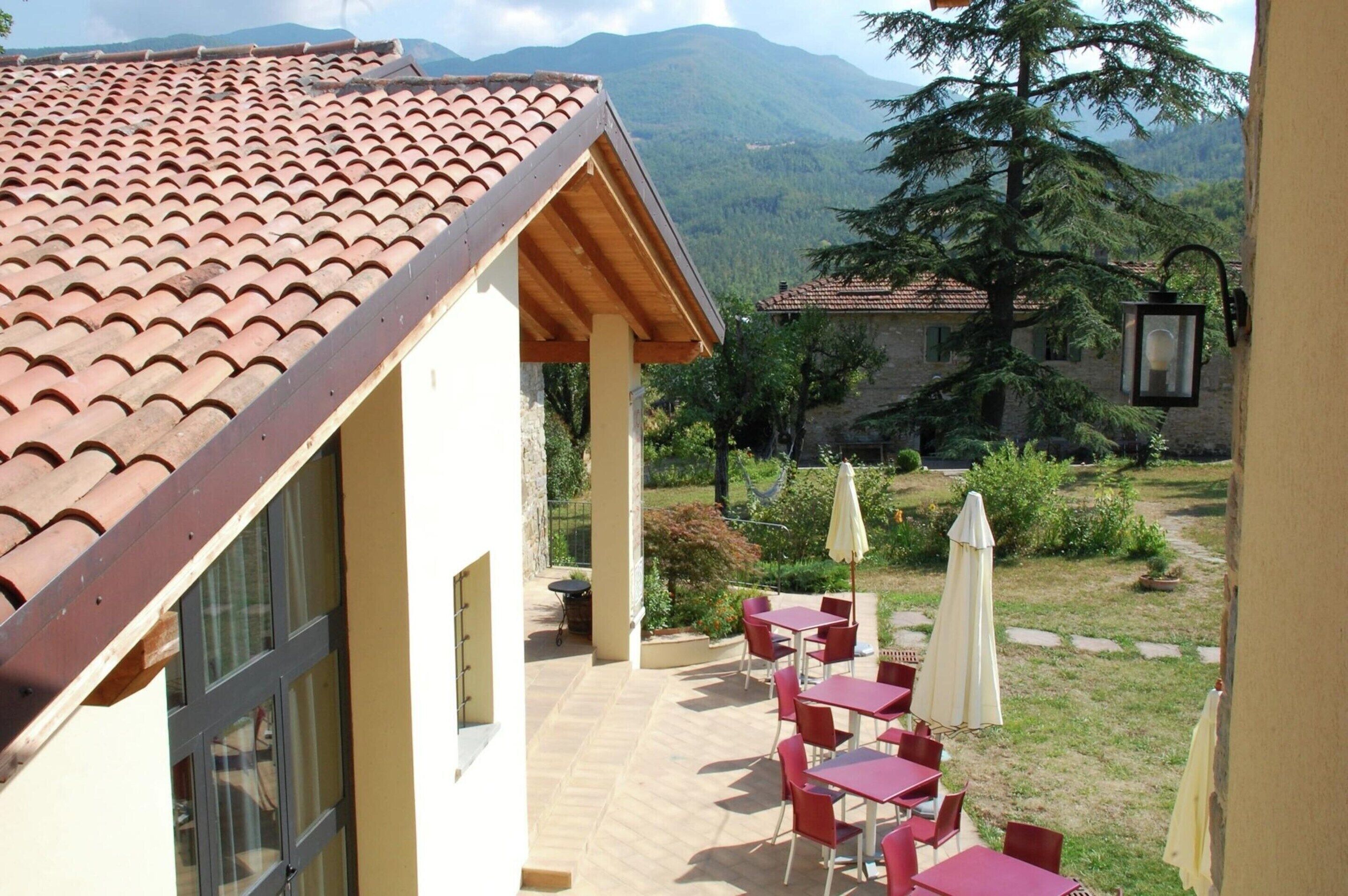 Una terraza con techo de tejas rojas, mobiliario exterior y vistas a las montañas.