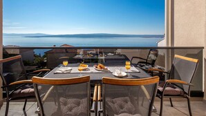 Ein Balkon mit gedecktem Frühstückstisch, mit Blick auf ein Gewässer und entfernte Landschaft.