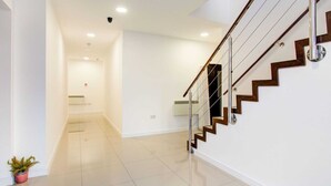 A modern interior with a staircase, white walls, and a potted plant. - Simplistic Apartment in Milton Keynes Near Willen Lake (Milton Keynes)