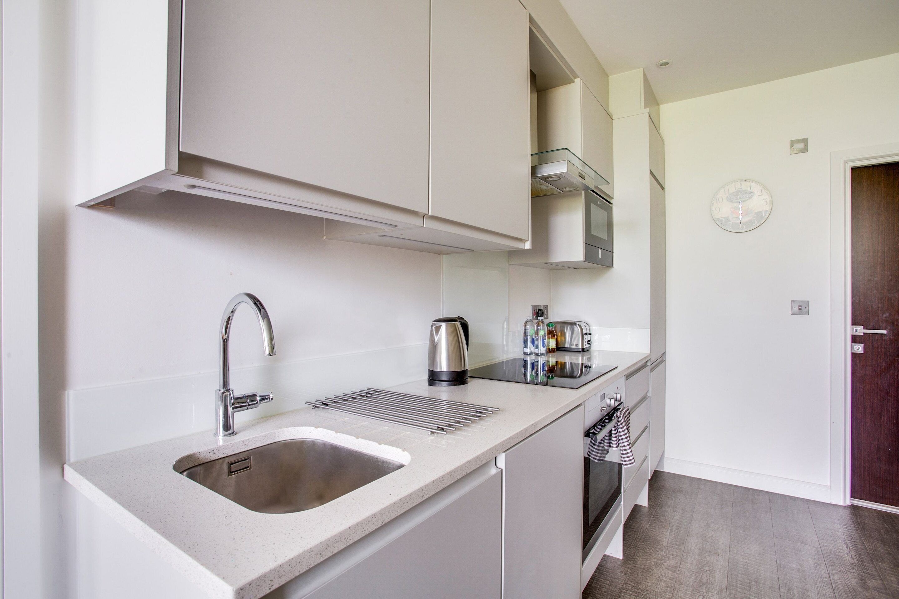 A modern kitchen with a stainless steel sink, a kettle, and a toaster.