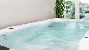 A hot tub with a view of a garden and a building in the background. - Cozy Holiday Home in Olst-wijhe With Swimming Pool (Olst)