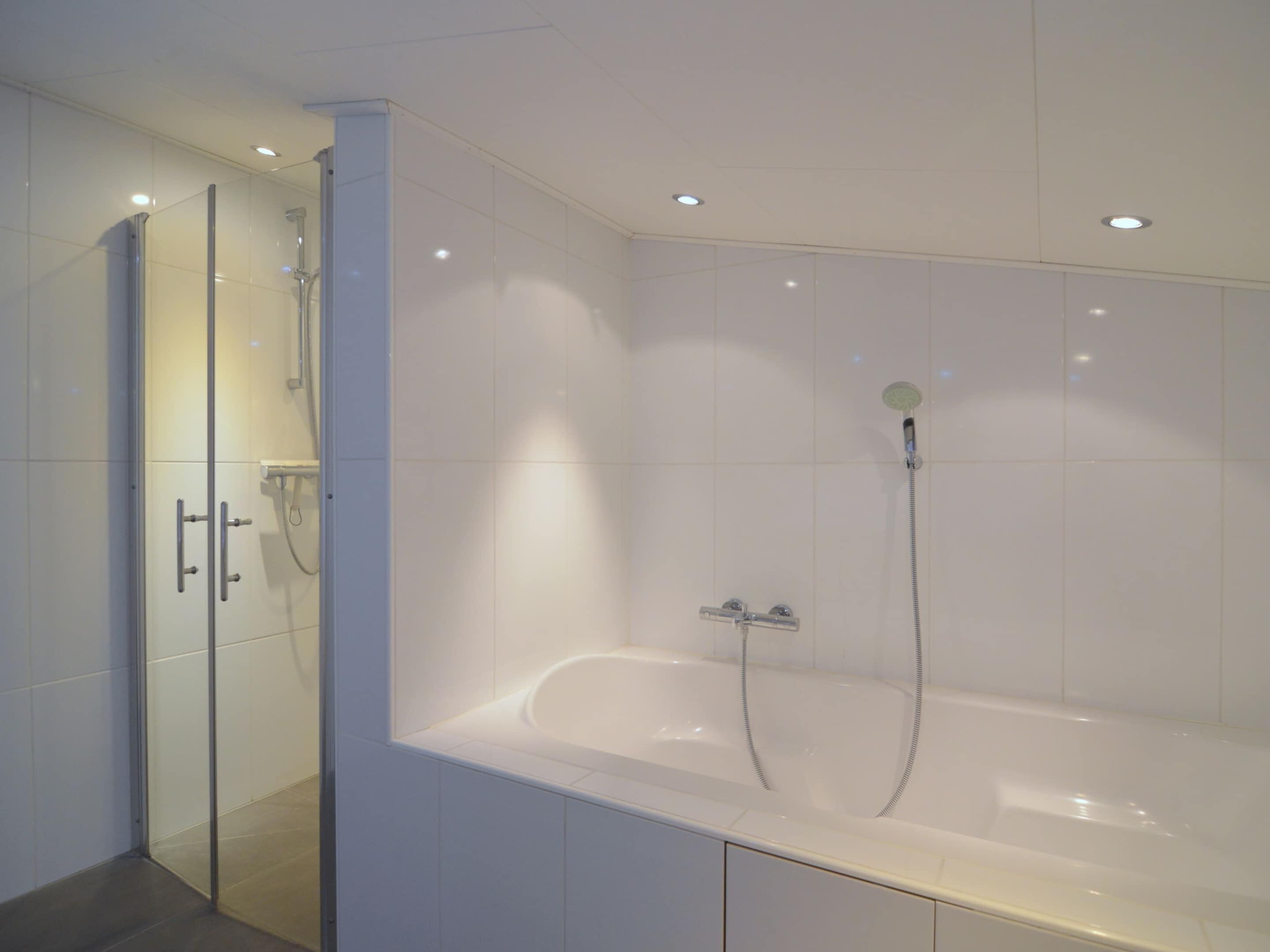 Un baño moderno con ducha a ras de suelo, bañera y cabina de ducha acristalada.