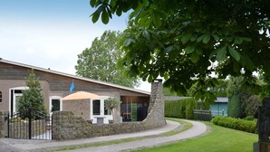 A building with a stone wall, a paved walkway, and a grassy area. - Cozy Holiday Home in Olst-wijhe With Swimming Pool (Olst)