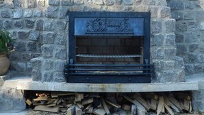 A stone fireplace with a metal grate, surrounded by a stone wall. - Cozy Holiday Home in Olst-wijhe With Swimming Pool (Olst)