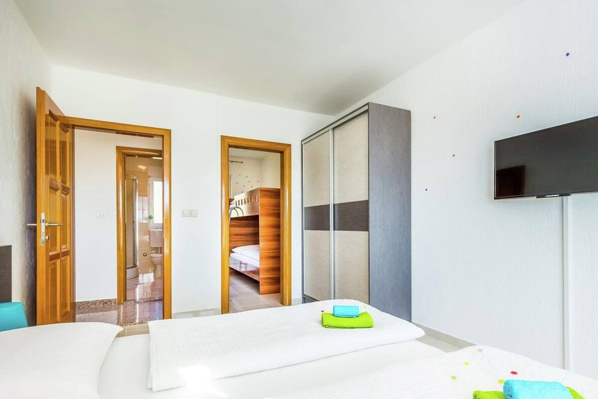 A hotel room with a bed, a TV, a wardrobe, and a bathroom visible through an open door.
