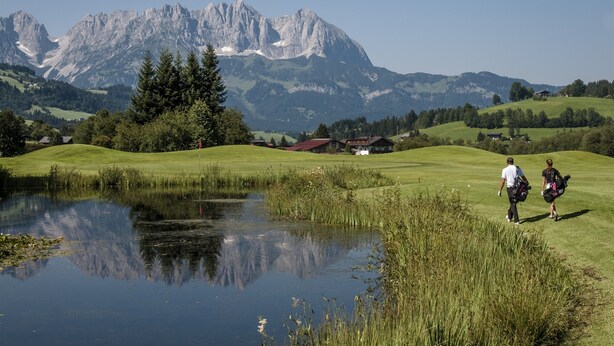 A golf course with a pond, trees, and mountains in the background. - Modern Apartment Near Ski Area in Brixen im Thale (Brixen im Thale)