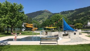 A park with a water play area, a yellow slide, and a blue canopy. - Modern Apartment Near Ski Area in Brixen im Thale (Brixen im Thale)