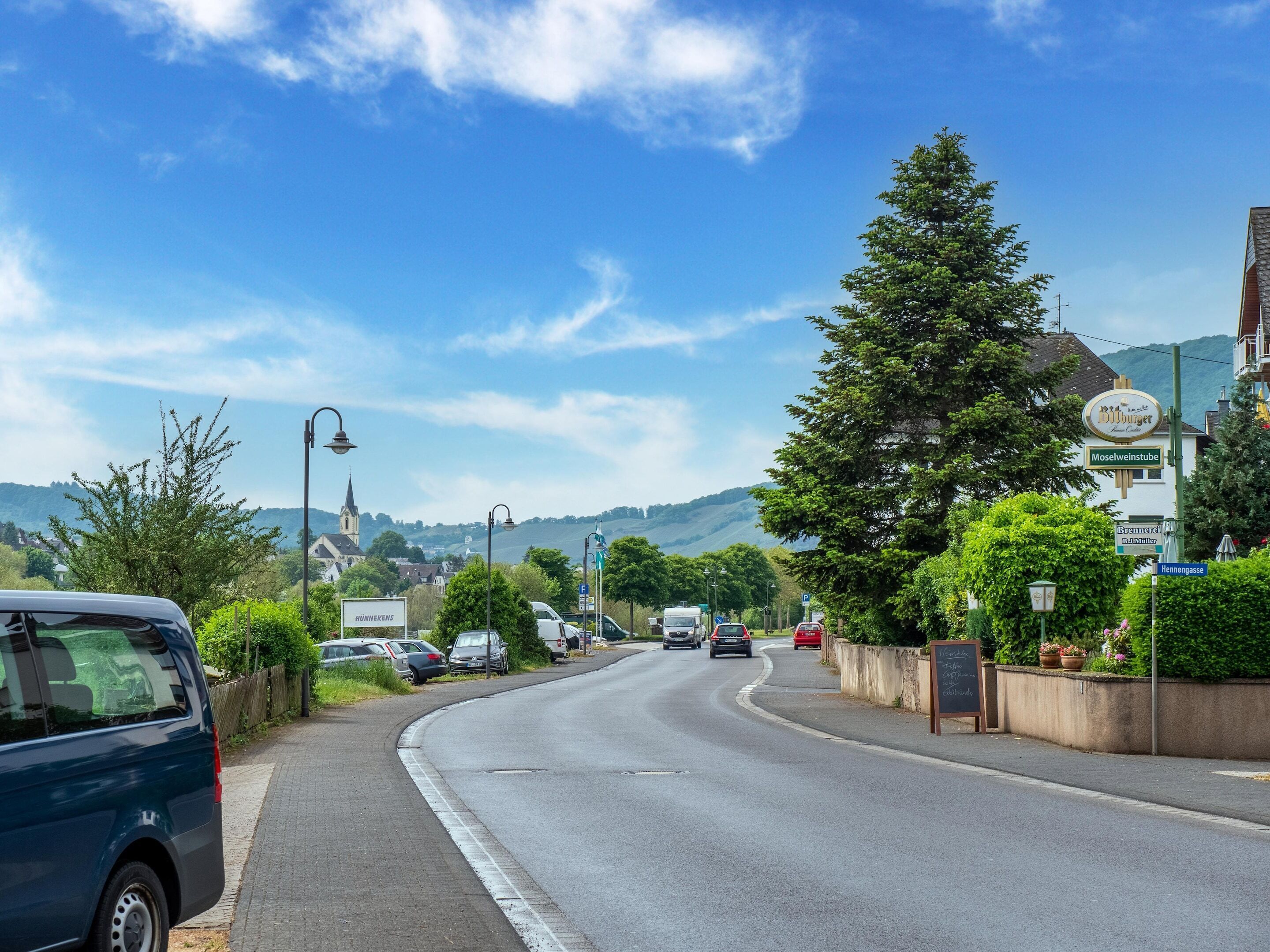 A road with cars, a church, and a sign for 'Hennengasse'.