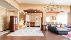 A spacious living room with patterned wallpaper, a fireplace, a chandelier, and a modern sofa set. - Cheerful Holiday Home in Kinheim With Mountain Views (Kinheim)