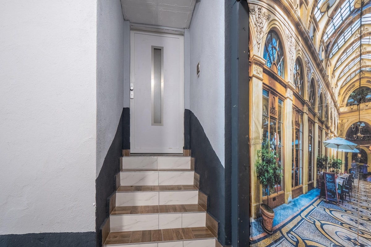 A staircase leading to a room with a view of a grand, ornate building with a glass ceiling.
