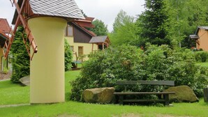 Un moulin à vent traditionnel, un banc en bois et un mur de pierre, le tout dans un jardin luxuriant.