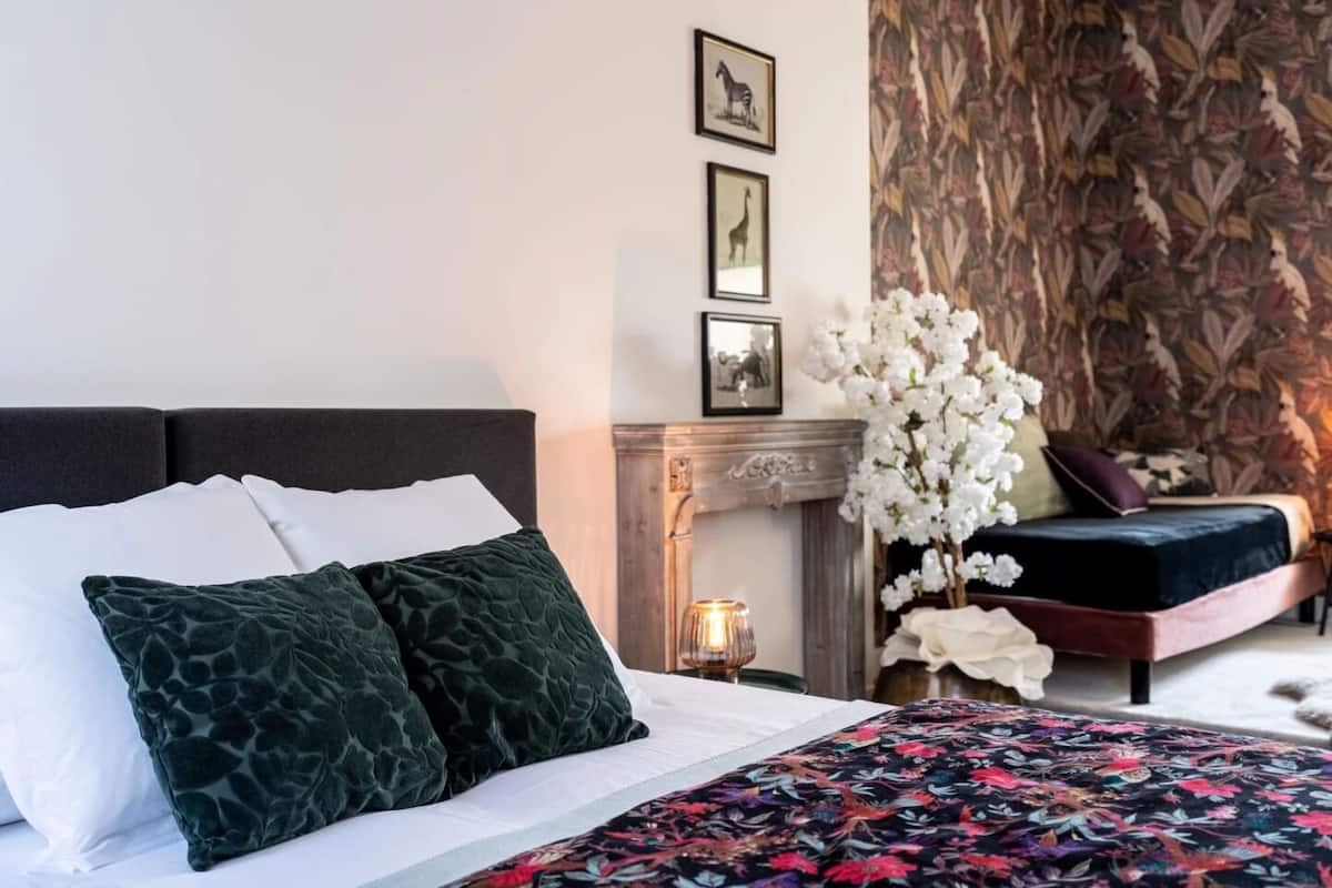 A bedroom with a bed, a fireplace, and framed pictures on the wall.