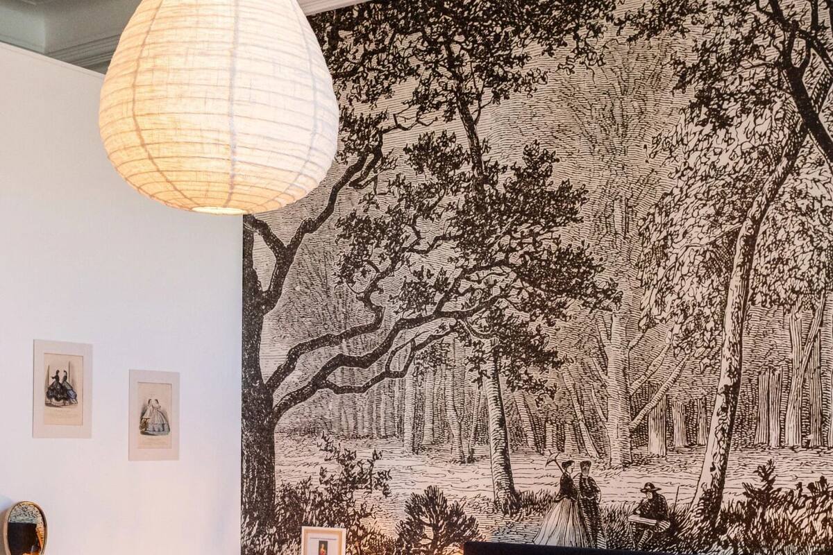 A bedroom with a large bed, a desk, a chair, and a hanging light fixture.