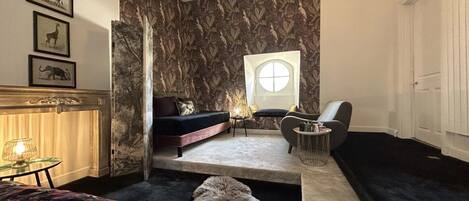 Une chambre à coucher avec un lit, un canapé, une chaise, une petite table et une fenêtre.
